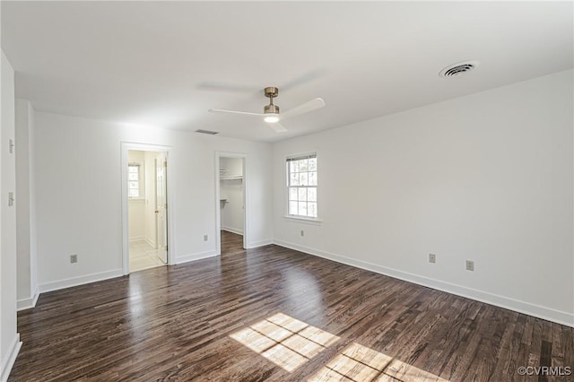 unfurnished bedroom with a spacious closet, baseboards, visible vents, and dark wood-style flooring