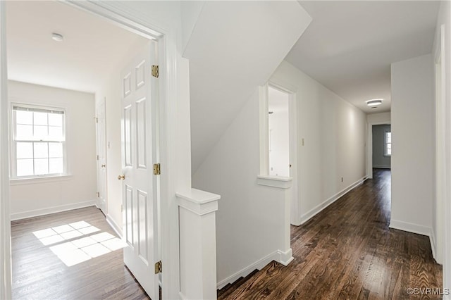 hall with baseboards, an upstairs landing, and wood finished floors