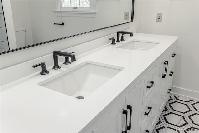 bathroom featuring double vanity, baseboards, and a sink