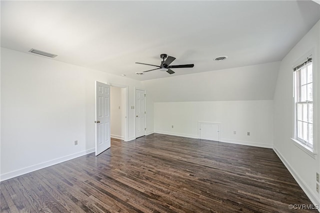 interior space featuring lofted ceiling, dark wood-style floors, visible vents, and baseboards