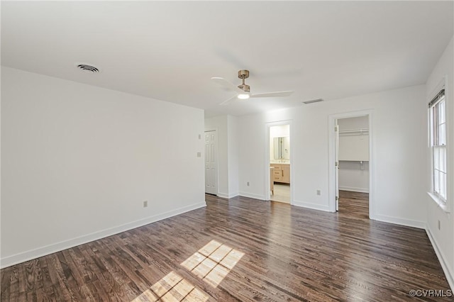 empty room with a ceiling fan, baseboards, visible vents, and dark wood-style flooring