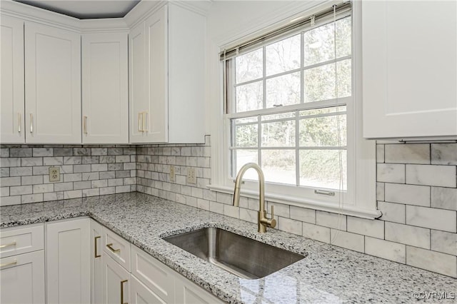 kitchen featuring white cabinetry, decorative backsplash, and a sink