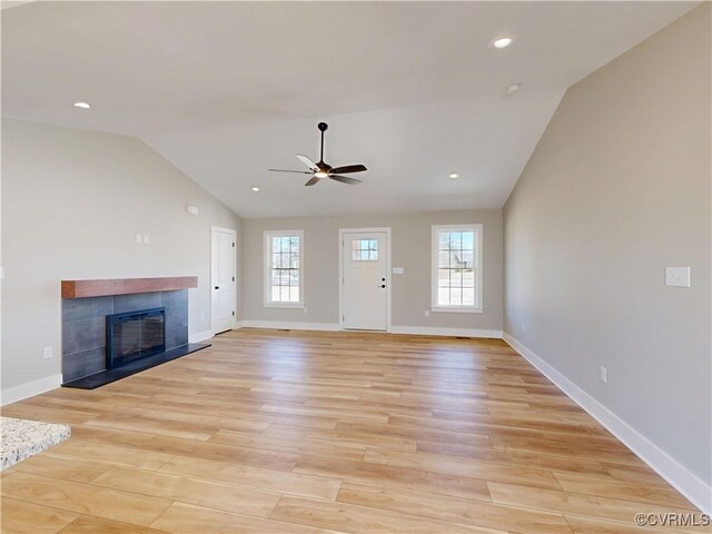 unfurnished living room featuring lofted ceiling, light wood-style flooring, a fireplace, and baseboards