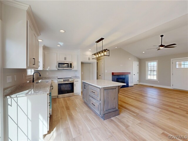 kitchen with pendant lighting, white cabinetry, appliances with stainless steel finishes, light wood finished floors, and lofted ceiling