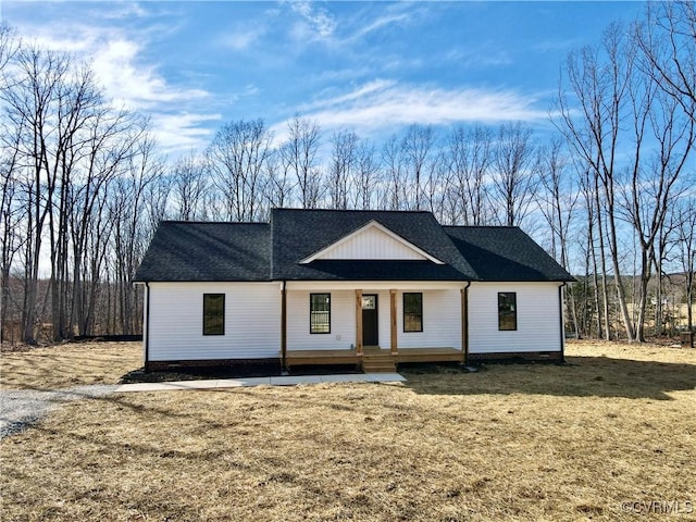 modern farmhouse style home with covered porch, a front lawn, and roof with shingles