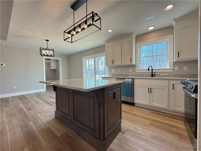 kitchen with a wealth of natural light, stainless steel dishwasher, a center island, black / electric stove, and light wood finished floors