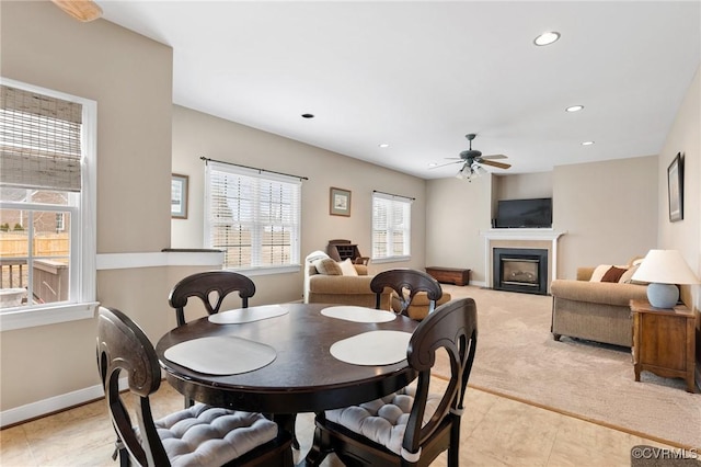 dining room featuring a ceiling fan, baseboards, recessed lighting, a fireplace, and light carpet