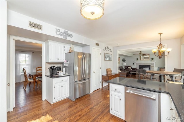 kitchen featuring visible vents, white cabinets, appliances with stainless steel finishes, and a brick fireplace