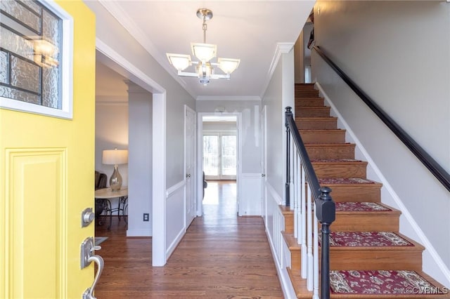 foyer featuring crown molding, baseboards, stairs, wood finished floors, and a notable chandelier