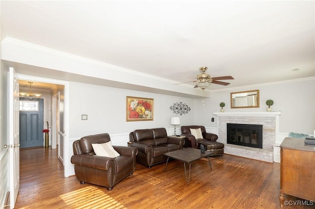 living room with a ceiling fan, a fireplace, wood finished floors, and crown molding