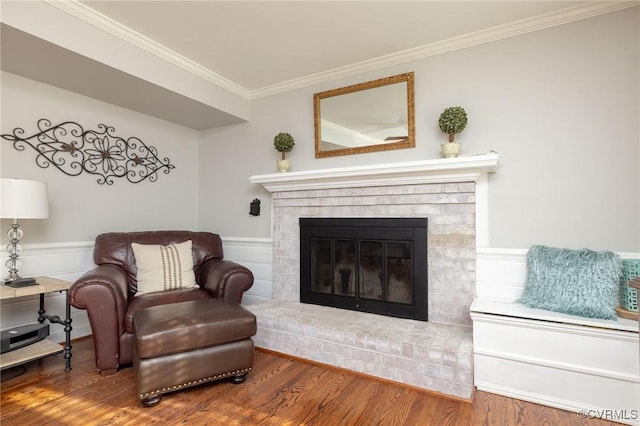 living area with a brick fireplace, wood finished floors, and ornamental molding