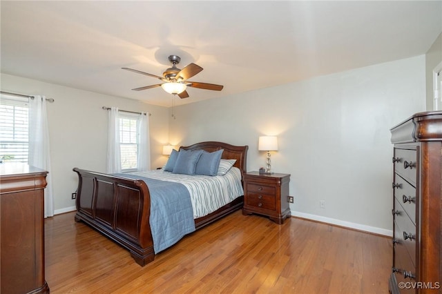 bedroom with light wood-style flooring, a ceiling fan, and baseboards