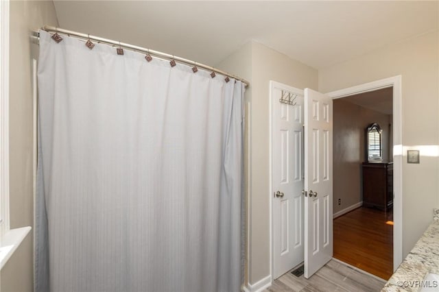 bathroom featuring curtained shower and wood finished floors