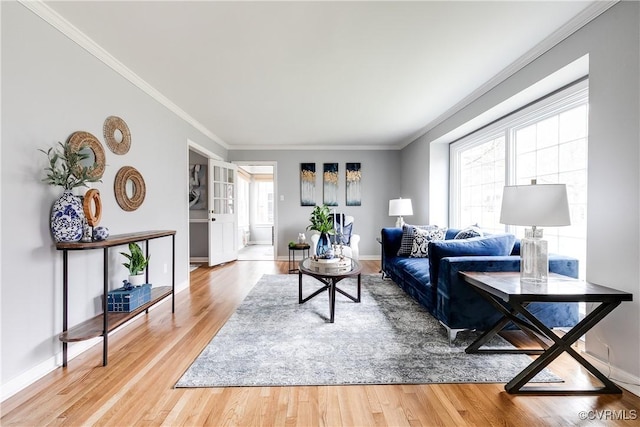 living room with baseboards, light wood finished floors, and ornamental molding