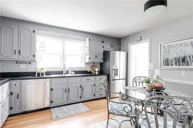 kitchen with dark countertops, gray cabinets, stainless steel appliances, and a sink