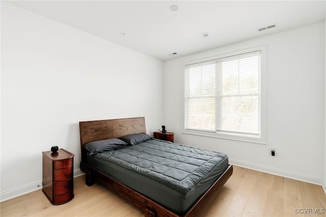 bedroom with light wood-style flooring, baseboards, and visible vents