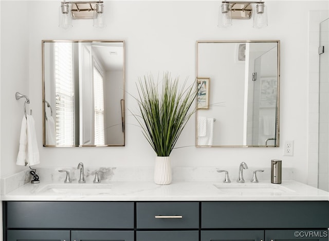 bathroom featuring a sink, a shower with shower door, and double vanity