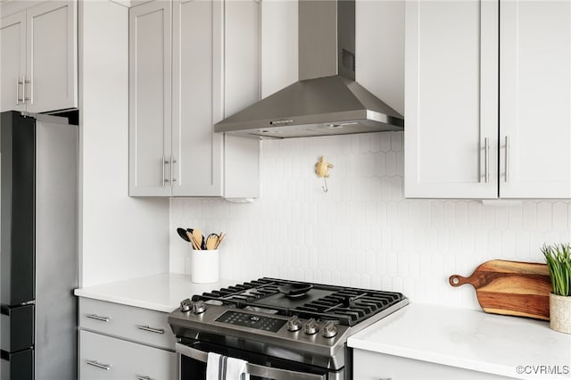 kitchen with light countertops, wall chimney exhaust hood, tasteful backsplash, and appliances with stainless steel finishes