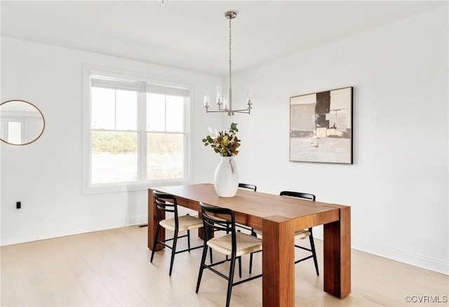 dining room with light wood finished floors, a chandelier, and baseboards