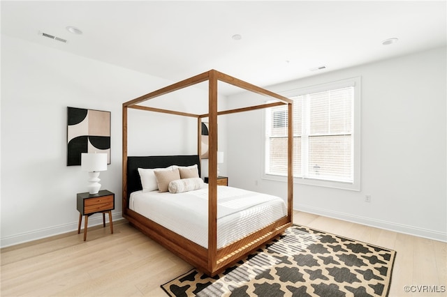 bedroom featuring visible vents, light wood-type flooring, and baseboards