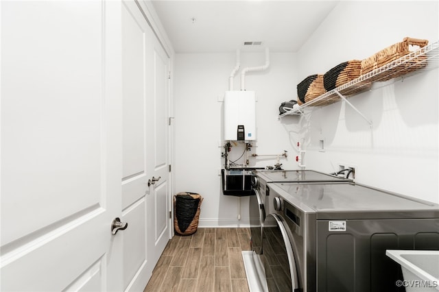 washroom featuring visible vents, water heater, separate washer and dryer, laundry area, and wood tiled floor