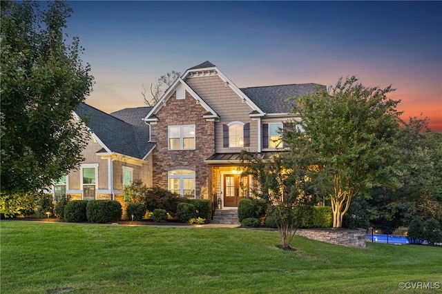 craftsman house with stone siding and a yard