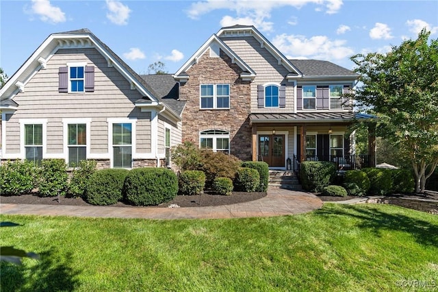 craftsman inspired home featuring a front yard, covered porch, metal roof, stone siding, and a standing seam roof