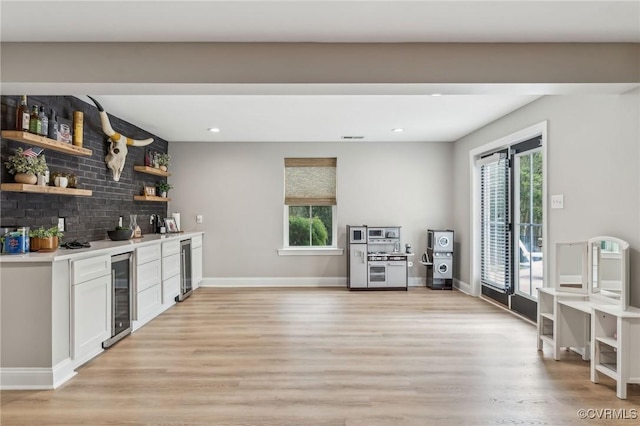 bar with beverage cooler, backsplash, light wood-style floors, and a wealth of natural light