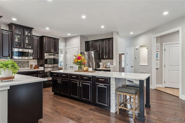 kitchen featuring dark wood finished floors, appliances with stainless steel finishes, a center island, and light countertops