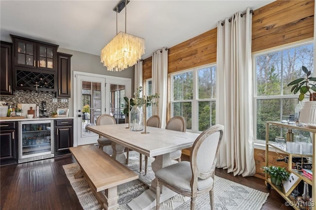 dining area featuring a chandelier, wine cooler, dark wood-type flooring, and wet bar