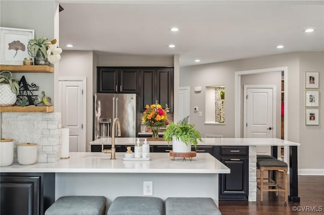 kitchen featuring a kitchen bar, a peninsula, light countertops, and stainless steel fridge