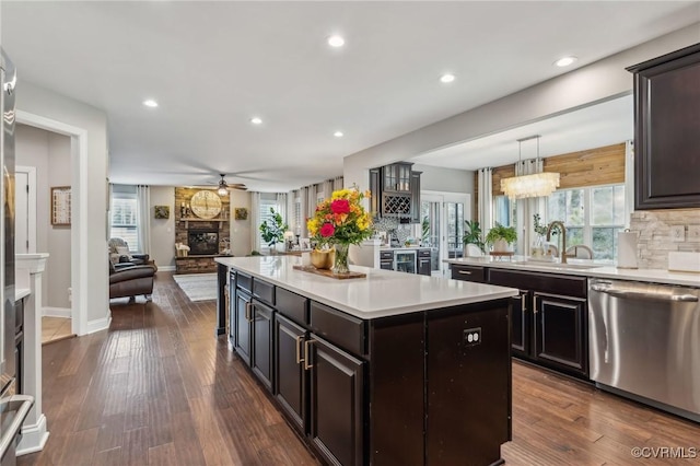 kitchen featuring a healthy amount of sunlight, a center island, dishwasher, light countertops, and a fireplace