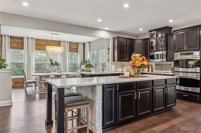 kitchen with decorative backsplash, appliances with stainless steel finishes, light countertops, and dark wood-type flooring