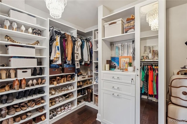 walk in closet with a notable chandelier and dark wood-type flooring