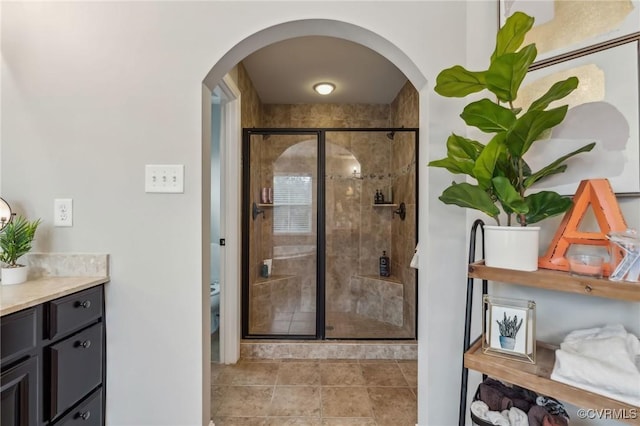 bathroom featuring vanity, tile patterned floors, toilet, and a stall shower