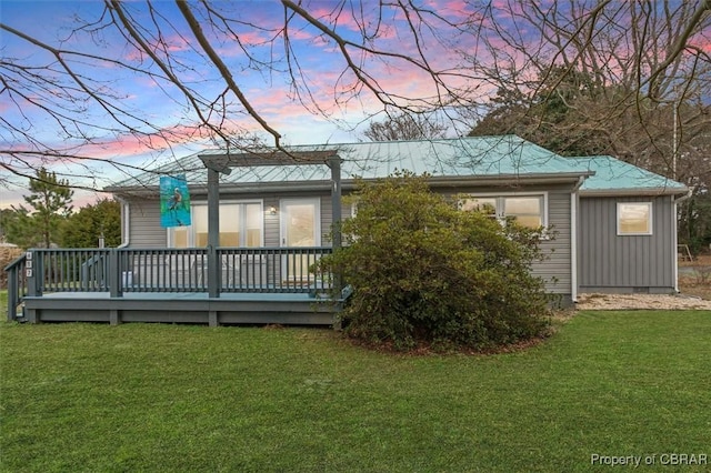 back of house at dusk featuring crawl space, a lawn, board and batten siding, and a wooden deck