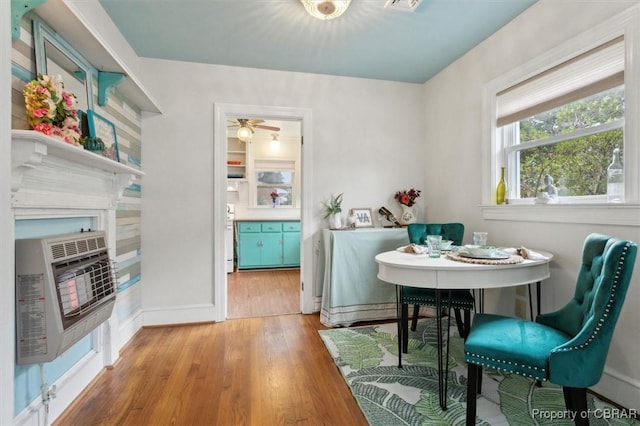 dining area with heating unit, baseboards, and wood finished floors