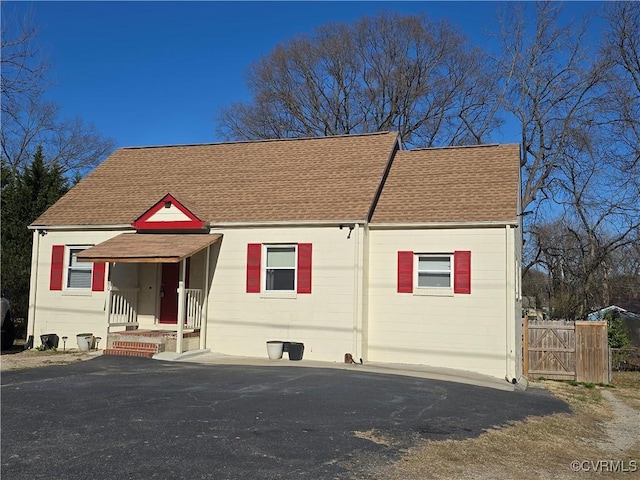 view of front of house featuring roof with shingles and a gate