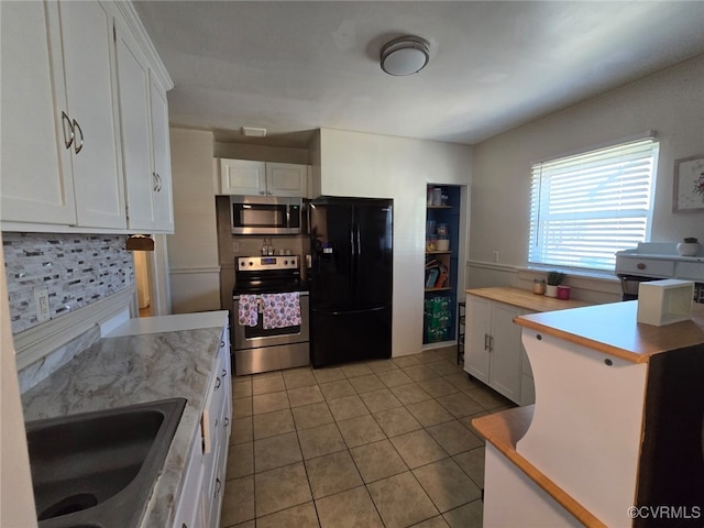 kitchen with light countertops, light tile patterned floors, stainless steel appliances, white cabinetry, and a sink