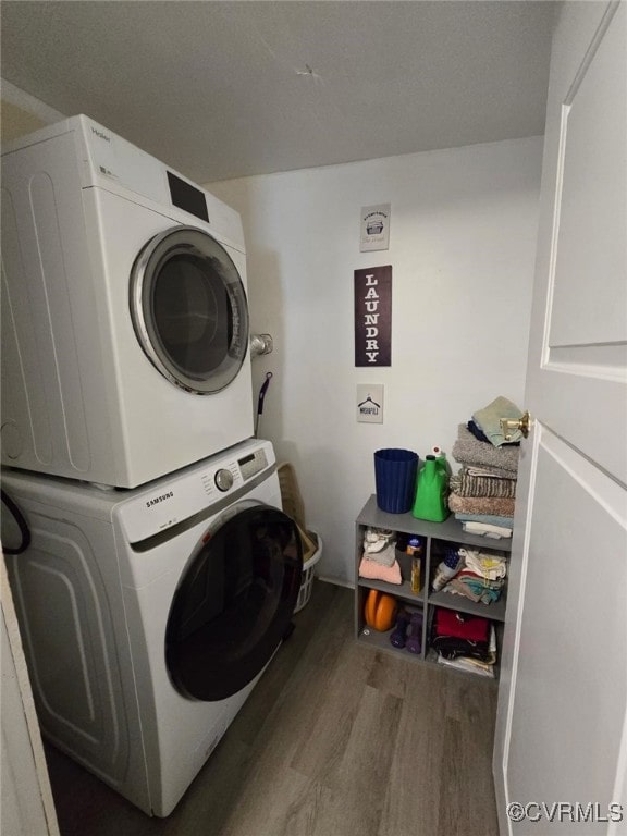 clothes washing area featuring laundry area, stacked washer / dryer, and wood finished floors