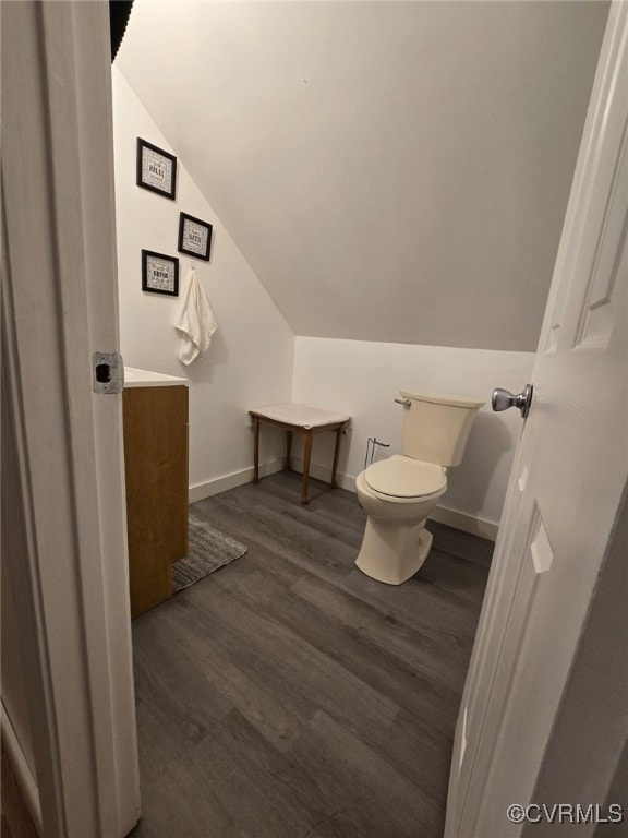 bathroom with vanity, wood finished floors, baseboards, vaulted ceiling, and toilet