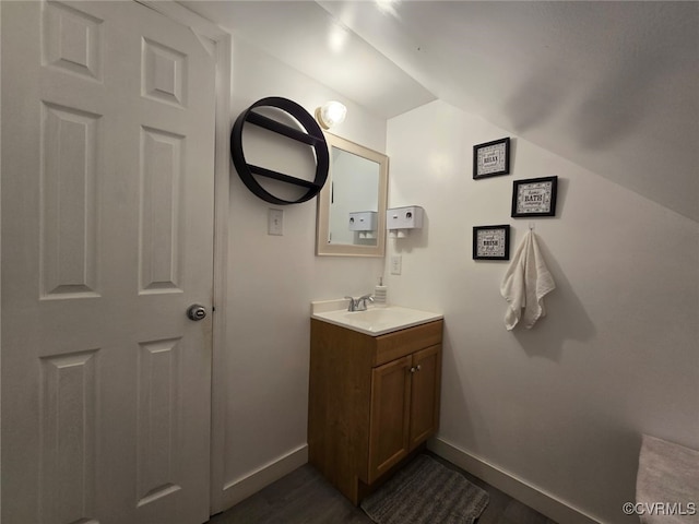 bathroom with vanity, lofted ceiling, wood finished floors, and baseboards