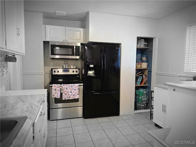 kitchen featuring a sink, appliances with stainless steel finishes, white cabinets, light tile patterned flooring, and light countertops