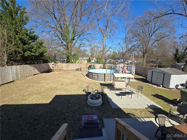 view of yard with a fenced in pool, a shed, a fenced backyard, an outdoor structure, and a patio area