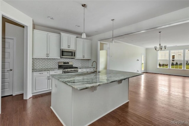 kitchen featuring dark wood finished floors, decorative backsplash, white cabinets, stainless steel appliances, and a sink