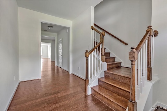 staircase featuring wood finished floors and baseboards