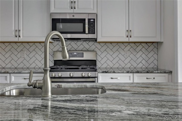 kitchen with white cabinetry, stainless steel microwave, and a sink