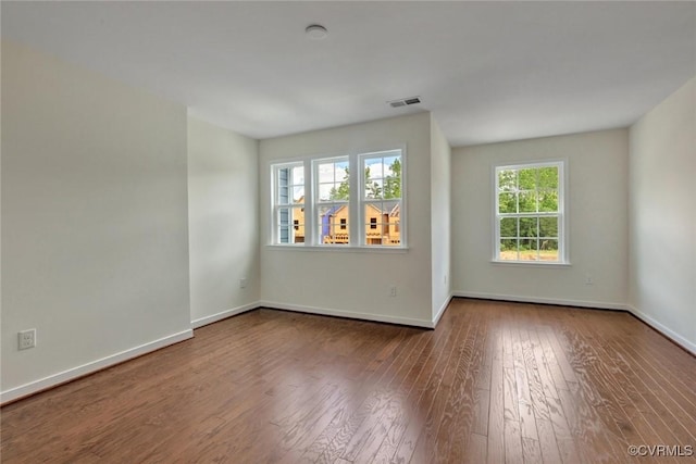 unfurnished room featuring visible vents, baseboards, and wood-type flooring