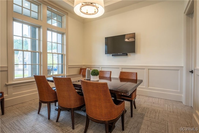 dining room with a chandelier, a decorative wall, and a wainscoted wall