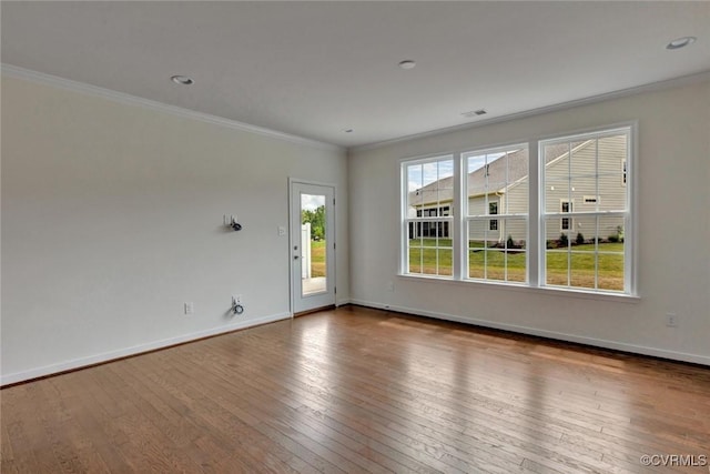 spare room with visible vents, ornamental molding, baseboards, and wood-type flooring